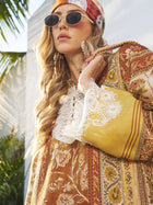A woman in the Social Queen Boho Lace Floral Print Dress, featuring botanical blooms and handcrafted lace panels, styled with sunglasses and a patterned headscarf, stands outdoors near greenery and a white wall.