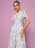 A woman models the Social Queen Botanical Embroidered Cutout Dress, featuring short sleeves and an A-line silhouette, against a solid pink background.