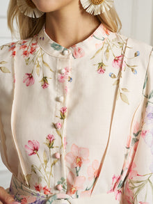 Close-up of a woman in Social Queen’s Botanical Print Cotton-Linen Dress, featuring a light floral pattern, fabric-covered buttons, and pleats. She pairs it with large floral earrings.