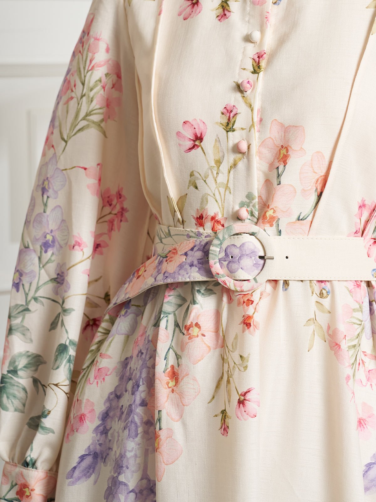 Close-up of Social Queen's Botanical Print Cotton-Linen Dress in soft hues, featuring pink and purple botanical motifs, fabric-covered buttons, and a matching belted waist with a round buckle.