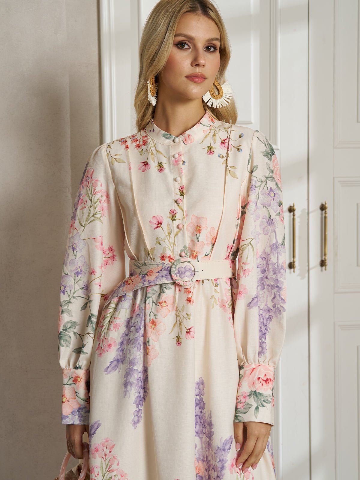 A woman stands indoors before white cabinets, looking slightly to the side, wearing the Social Queen Botanical Print Cotton-Linen Dress with a belt.