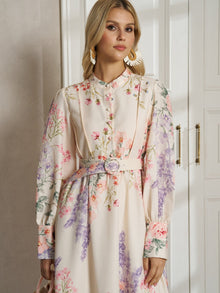 A woman stands indoors before white cabinets, looking slightly to the side, wearing the Social Queen Botanical Print Cotton-Linen Dress with a belt.