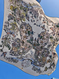 The Social Queen Butterfly Print Silk Scarf features elegant floral and butterfly patterns on white silk, gracefully waving against a clear blue sky.