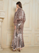 A woman stands with her back to the camera in an ornate, cream-colored room, wearing the Champagne Sequin Mermaid Skirt by Social Queen.