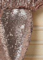 Close-up of the Social Queen Champagne Sequin Mermaid Skirt adorned with metallic sequins, set against a beige, textured background with horizontal lines.