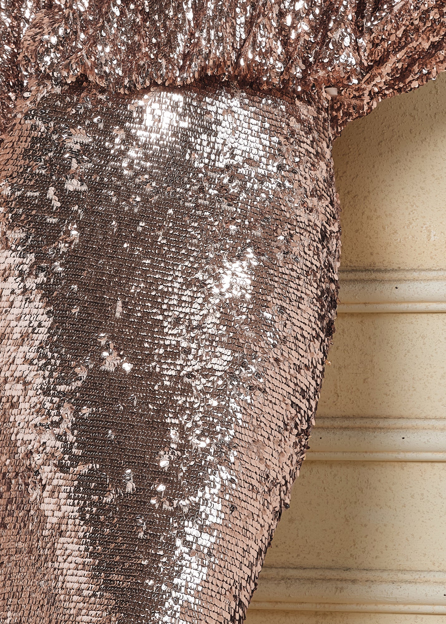 Close-up of the Social Queen Champagne Sequin Mermaid Skirt adorned with metallic sequins, set against a beige, textured background with horizontal lines.