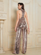 A woman stands indoors, facing away from the camera, wearing the Social Queen Champagne Sequin V-Neck Cami Top and holding a clutch.