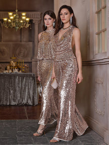 Two women stand indoors in party-ready Social Queen Champagne Sequin Wide-Leg Pants, holding small purses and posing near a decorated table and chandelier.