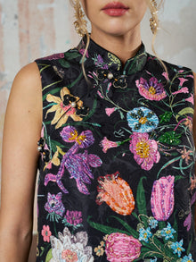 A woman wears the Social Queen Colorful Floral Mandarin Collar Dress, a sleeveless black piece featuring colorful floral embroidery, bead embellishments, and decorative buttons at the collar and shoulder.