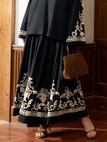 A person wearing the Social Queen Contrast Embroidered A-Line Skirt stands on a wooden floor in sandals, holding a brown cut-out purse.