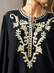 A person wears the Social Queen Contrast Embroidered Relaxed Blouse, a black top with intricate embroidery on the chest and neckline, featuring a relaxed silhouette.