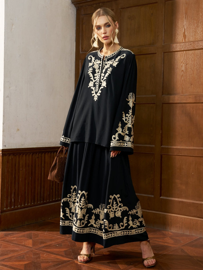 A woman wears the Social Queen Contrast Embroidered Relaxed Blouse indoors, styled with a brown handbag and heels, standing against a wooden-paneled wall.