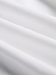 Close-up of the Cropped Embroidered Lace Panel Blouse by Social Queen, showing smooth white fabric with gentle folds and delicate hand-stitched lace accents.