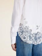 A person wearing the Social Queen Cropped Embroidered Lace Panel Blouse with blue jeans, shown from the side and back.