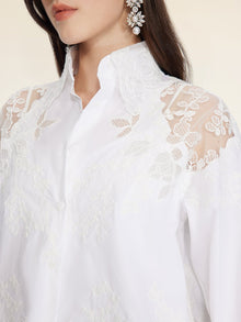 A woman wears the Social Queen Cropped Embroidered Lace Panel Blouse with hand-stitched lace floral shoulders, paired with ornate dangling earrings.
