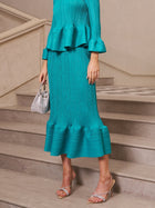 A person stands on stairs in the Social Queen Crystal-Embellished Pleated Peplum Set, styled with rhinestone sandals and a sparkling mini bag—a chic choice for any wedding guest.