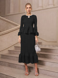 A woman stands on stone stairs wearing the Social Queen Crystal-Embellished Pleated Peplum Set—a chic wedding guest look—paired with a silver handbag and silver strappy heels.
