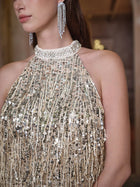 A woman models the Social Queen Crystal-Embellished Sequin Fringe Halter Dress with sparkling chandelier earrings. Only her lower face, neck, and upper torso are shown.