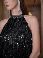 A woman wears the Social Queen Crystal-Embellished Sequin Fringe Halter Dress paired with long, dangling rhinestone earrings.