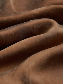 Close-up of soft, brown velvet fabric with visible folds and subtle sheen, echoing the luxurious look of Social Queen’s Crystal-Embellished Tencel Satin Blouse.