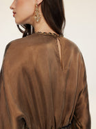 A woman in the Social Queen Crystal-Embellished Tencel Satin Blouse, featuring a relaxed fit, small back slit, and hand-set crystal trim, styled with large ornate gold earrings.