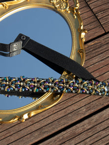 The Social Queen Crystal-Embellished Vintage Belt, featuring hand-set crystals and an adjustable buckle, is displayed on an ornate gold-framed mirror atop wooden planks.