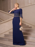 A woman in Social Queen's Crystal Fringe Fishtail Gown stands on a staircase, holding a small embellished clutch.