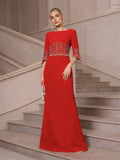 A woman in the Social Queen Crystal Fringe Fishtail Gown stands on a staircase in an elegant, neutral-toned interior.