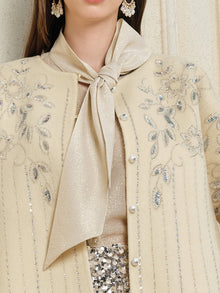 A woman wears Social Queen's Crystal Leaf Embroidered Wool Coat, styled with a shimmery neck scarf and a skirt detailed with leaf-patterned sequins.