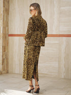 A woman in sunglasses wears the Social Queen Crystal-Trim Sequin Velvet Jacket with heeled sandals, standing indoors against a tiled wall.