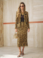 A woman stands indoors wearing a gold sequin skirt suit, a black lace top, sunglasses, sandals, and holding the Social Queen Crystal-Trim Sequin Velvet Jacket with a small gold handbag.
