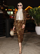 A woman in sunglasses wears the Social Queen Crystal-Trim Sequin Velvet Jacket and matching skirt, paired with a white ruffled blouse and beaded purse, as she walks outdoors at night.