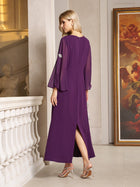 A woman stands indoors in a Social Queen Elegant Beaded Split-Sleeve Dress, featuring sheer sleeves. She faces away, wearing silver heels beside a white railing and a large framed painting.