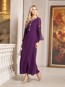 A woman stands indoors by a white railing and large framed painting, wearing the Social Queen Elegant Beaded Split-Sleeve Dress—an A-line cocktail evening gown with a high waist and silver embellishments.