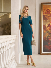 A woman stands indoors by a white balustrade and large framed painting, wearing the Social Queen Elegant Rhinestone-Embellished Dress in teal with a fitted knee-length silhouette and sparkling neckline, paired with a small handbag.
