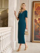 A woman wears the Social Queen Elegant Rhinestone-Embellished Dress in teal, knee-length and fitted, standing indoors by a staircase with a small gold bag and gold heels.