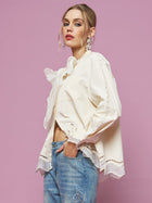 A woman models the Social Queen Embroidered Cutout Bow-Tie Blouse with blue jeans, standing in front of a light pink background and looking at the camera.