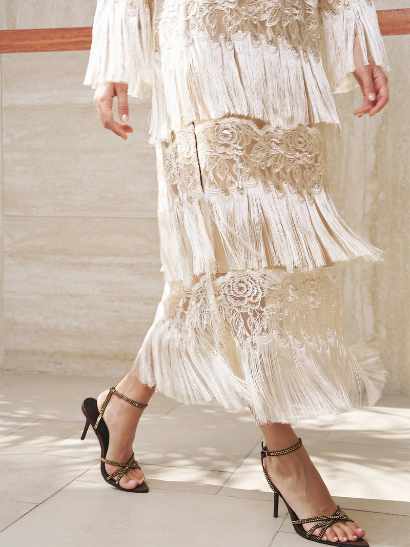 A woman wearing the Social Queen Embroidered Fringe Lace Crystal-Trimmed Dress with a kaftan-inspired silhouette.