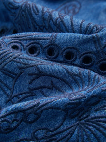 Close-up of Social Queen's Embroidered Jacquard Denim Dress, showcasing floral jacquard embroidery and circular cut-out details on blue denim fabric.