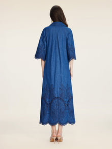 A woman faces away, wearing the Social Queen Embroidered Jacquard Denim Dress with scalloped edges and beige heeled sandals.