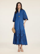 A woman wears the Social Queen Embroidered Jacquard Denim Dress—a blue, relaxed fit, midi-length design with short sleeves—paired with a round straw bag and nude sandals against a neutral background.