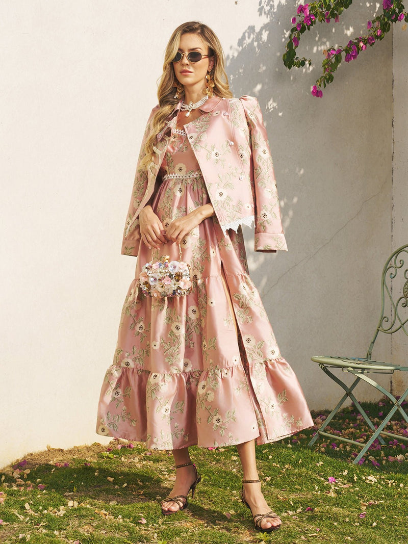 A woman in a pink floral Embroidered Jacquard Lace-Trimmed Jacket by Social Queen stands outdoors by a wall and green chair, wearing sunglasses, sandals, and holding a matching floral handbag.