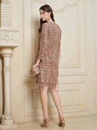 A woman stands indoors, facing away, wearing the Social Queen Embroidered Sequin Tassel Mini Dress with high-heeled sandals and holding a small clutch.