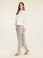 A woman in profile wears the Social Queen Embroidered Wool Jacket with Pearl Accents, a ruffled blouse, metallic fringe skirt, gold earrings, and high-heeled sandals against a neutral background.