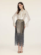 A woman wears the Social Queen Ethereal Metallic Ruffle Silk Blouse, styled with layered gold belts and earrings, and a metallic sequin fringe skirt, standing against a plain light background.