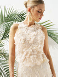 A woman models the Social Queen Floral Appliqué Sheer Sleeveless Top with 3D floral details, paired with large tassel earrings, standing before green palm leaves.