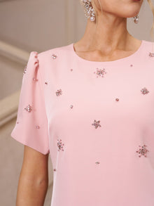A woman wears the Social Queen Floral Beaded Puff Sleeve Dress in light pink with pearl drop earrings, shown from the shoulders up—a stylish pick for a wedding guest.