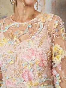 Close-up of a woman wearing the Floral Beaded Sheer Gown by Social Queen, featuring pastel pink sheer fabric with 3D floral appliqué, sequins, beading, and textured embroidery.