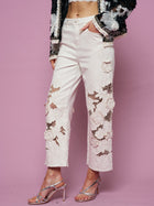 Wearing Social Queen’s Floral Cutout High-Rise Jean, a crop top, black embellished jacket, and strappy high-heeled sandals, a person poses against a pink background.