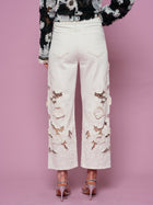 Model wears Social Queen Floral Cutout High-Rise Jean in white and a black floral top, standing against a pink background, shown from the back.